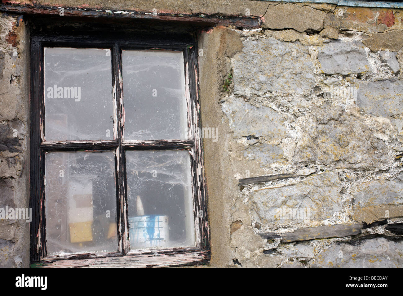Telas de araña de cristal cubierto con pintura desconchada en el bastidor contra una pared de piedra decrépito Foto de stock
