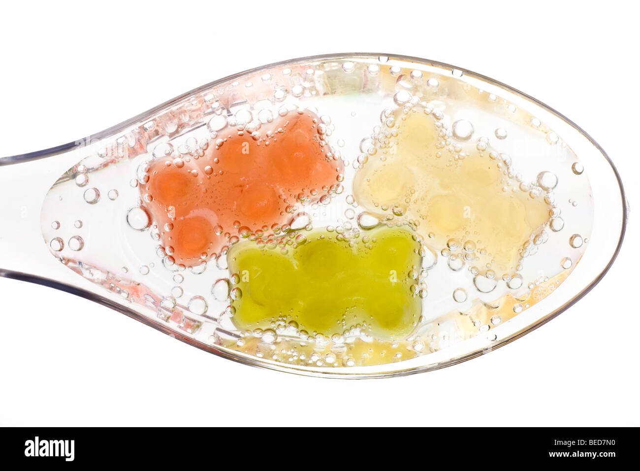 Los osos Gummi en agua transparente cucharas Foto de stock