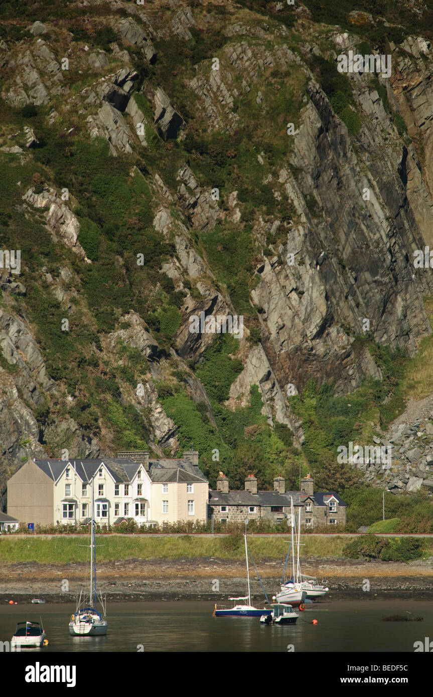 Una fila de casas de playa empequeñecidos por enormes acantilados en Barmouth, estuario Mawddach, el Parque Nacional de Snowdonia, Gwynedd, al norte de Gales, Reino Unido Foto de stock