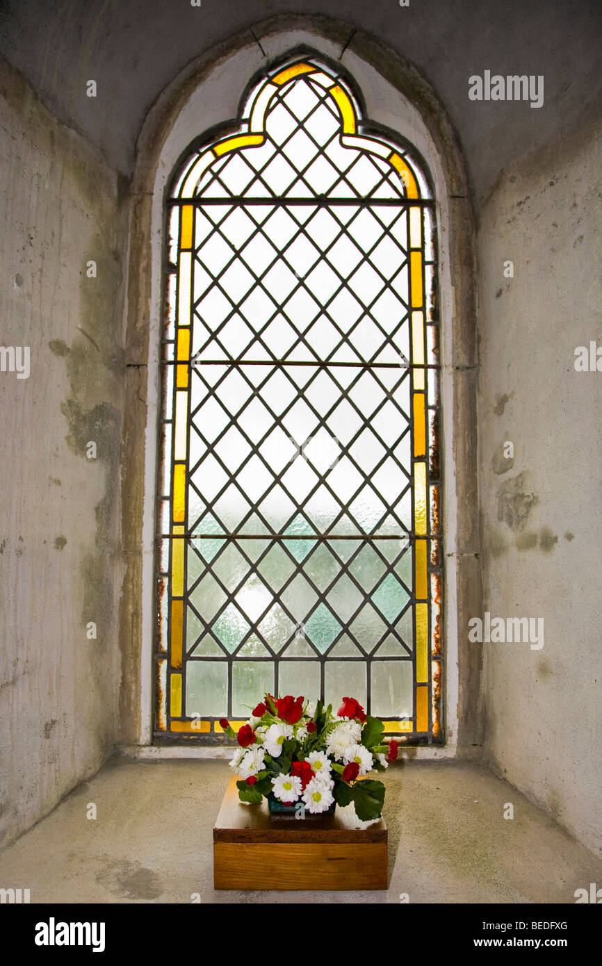 Pequeña ventana lateral de una capilla escocesa con pequeña caja de flores rojas y blancas en preparación para la boda Foto de stock