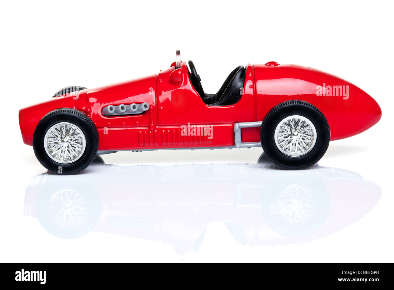 Antiguo coche de carreras de juguete rojo sobre un fondo blanco con reflexión. Foto de stock