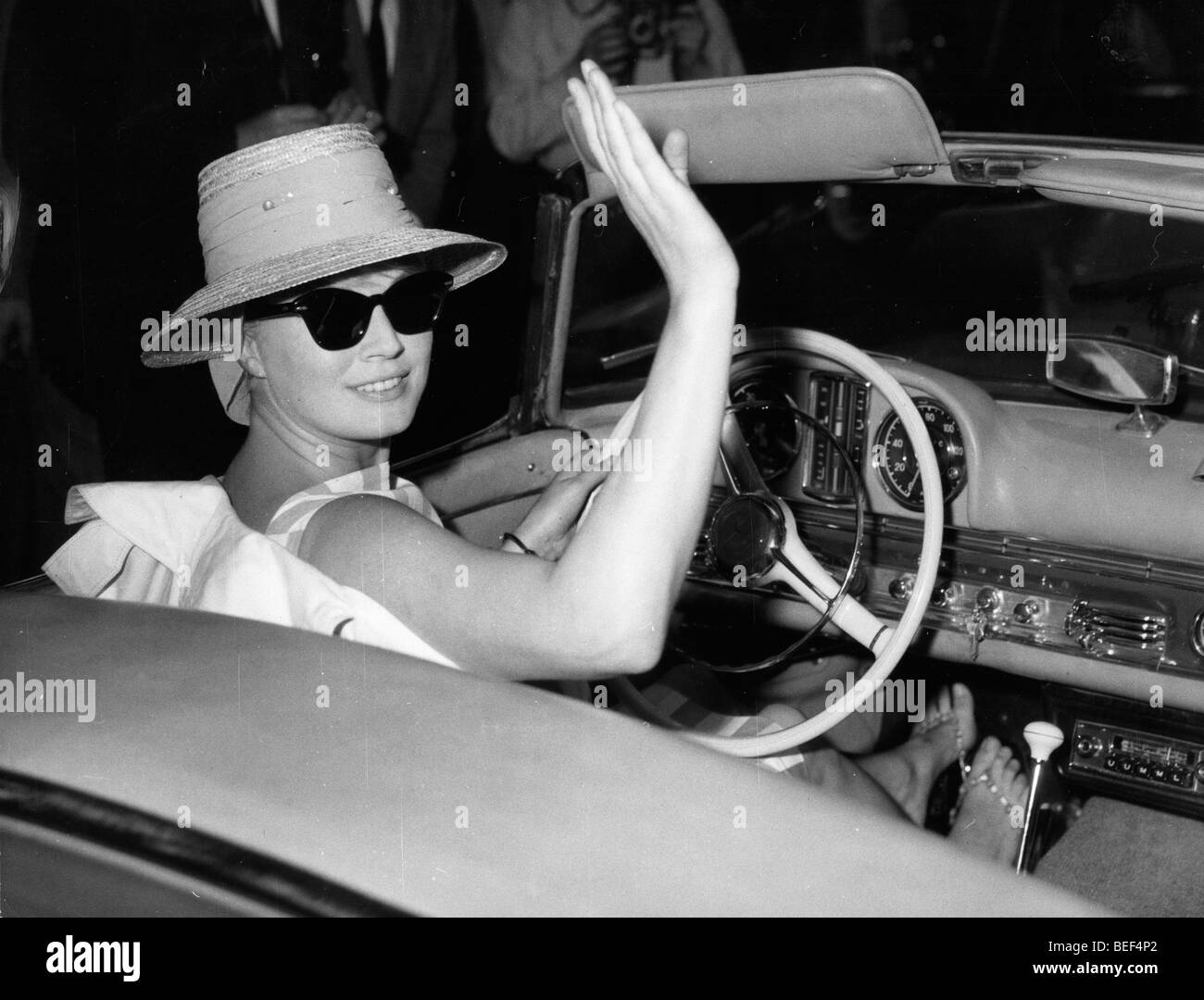 La actriz sueca Anita Ekberg olas mientras conduces un coche convertible. Foto de stock