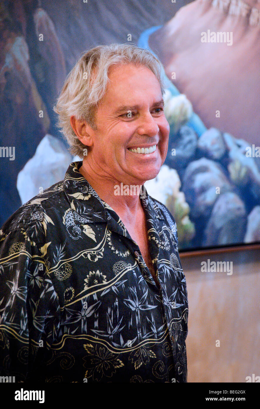 Talentosa y reconocida artista Doug West está ante una de sus obras en su galería en Arroyo Seco, New Mexico. Foto de stock
