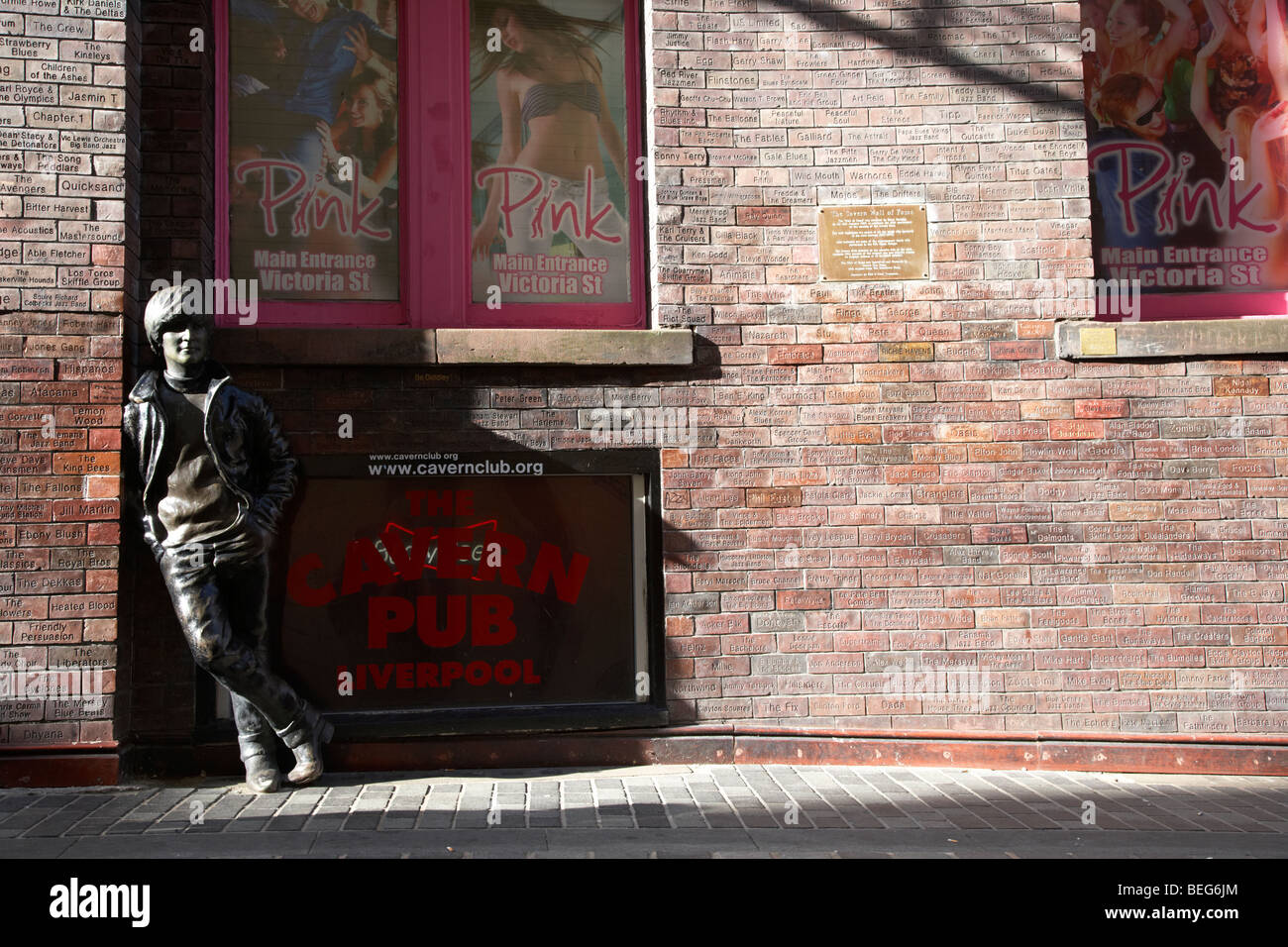 La estatua de John Lennon y la pared de la fama de la caverna en Mathew Street, en el centro de la ciudad de Liverpool, cuna de los beatles Foto de stock