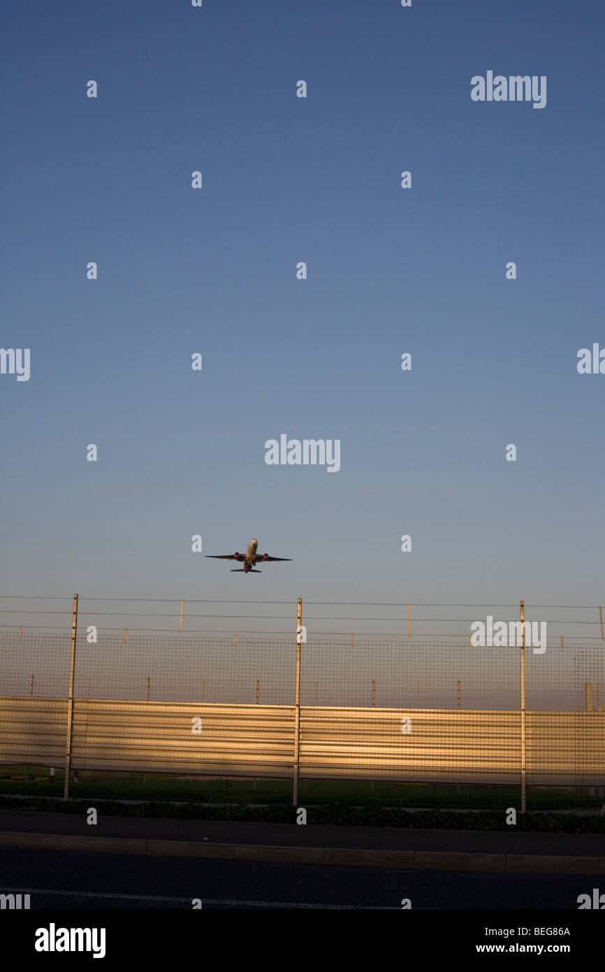 Un avión cruza el perímetro vallado de seguridad en el aeropuerto de Heathrow, en su camino a un destino internacional. Foto de stock