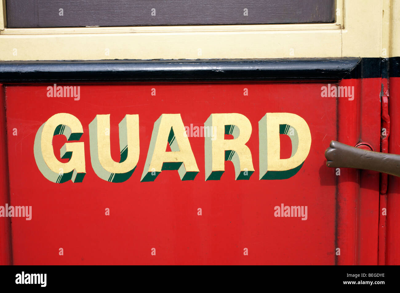 Letras amarillas diciendo 'guard' en un viejo vagón de tren rojo Foto de stock