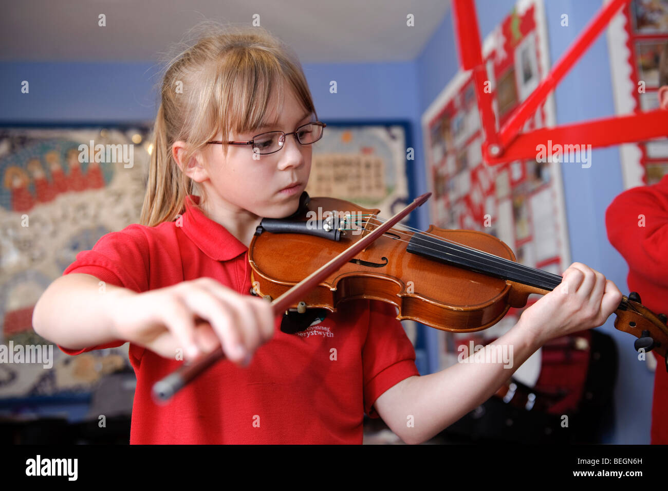 Un joven alumno de primaria aprendiendo a tocar el violín en la escuela, Gales, Reino Unido Foto de stock