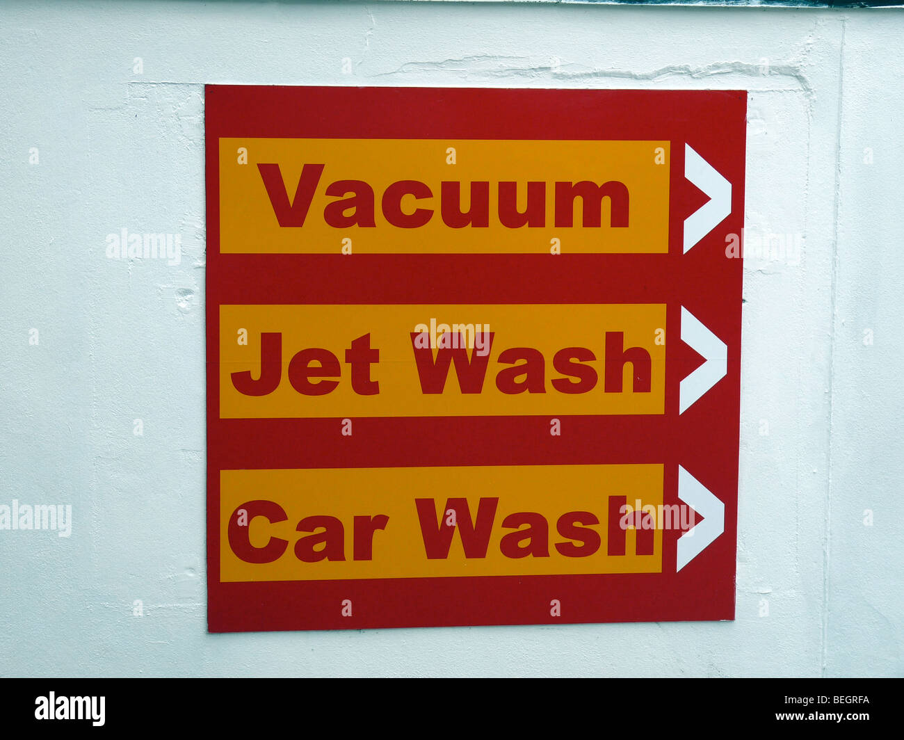 Rojo y amarillo signo vacío,lavado,car wash contra una pared pintada en blanco en una estación de servicio Foto de stock