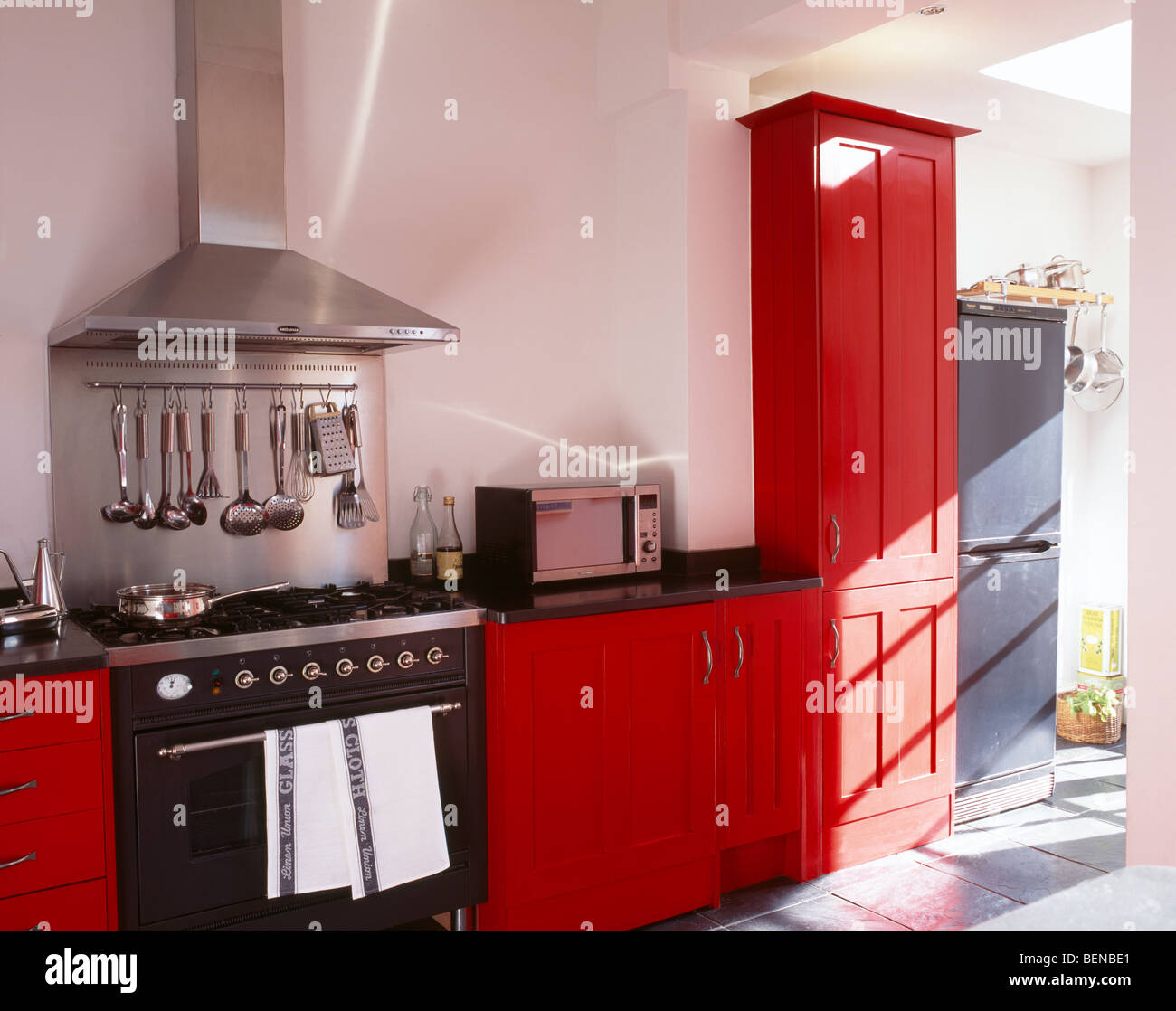 Extractor de acero inoxidable y salpique encima negro gama de microondas en  la moderna cocina blanca con rojo montado unidades de extensión Fotografía  de stock - Alamy