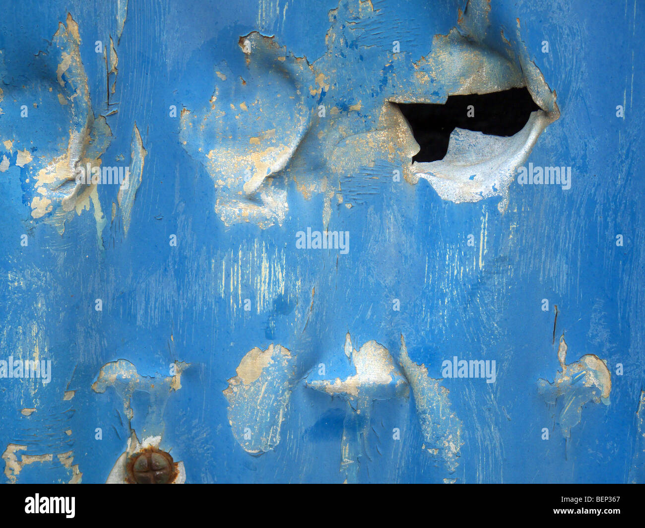Jagged perforados en una lámina pintada de azul de metal viejo Foto de stock