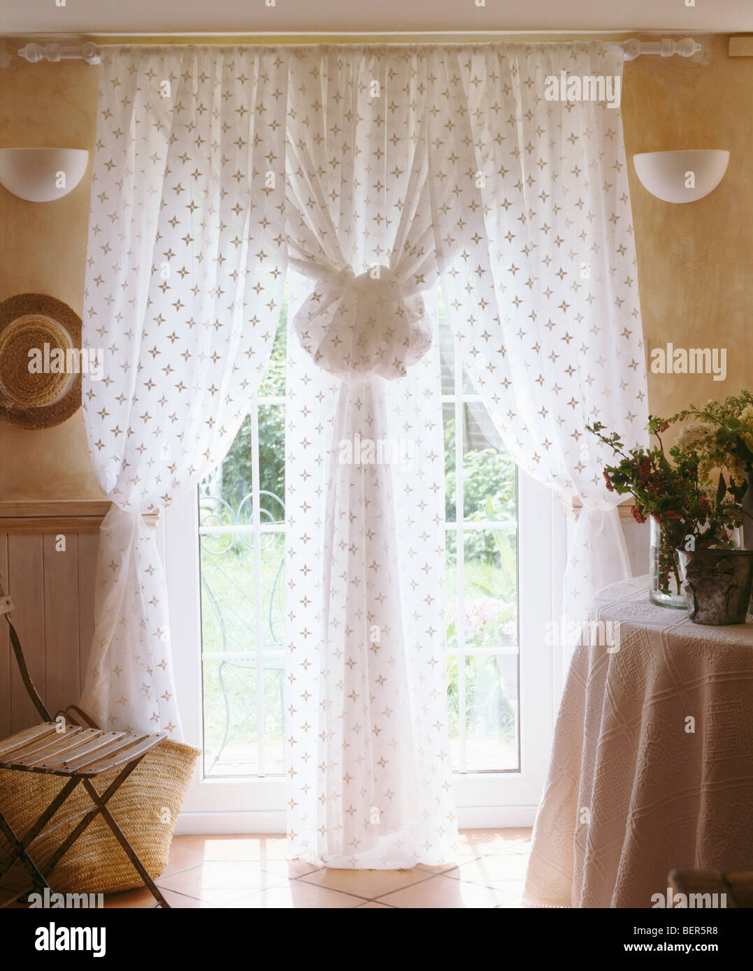 Cortinas blancas encima de una cama individual con ropa de cama blanca y  cojines en dormitorio tradicional con imágenes grandes y telas ciegos  Fotografía de stock - Alamy