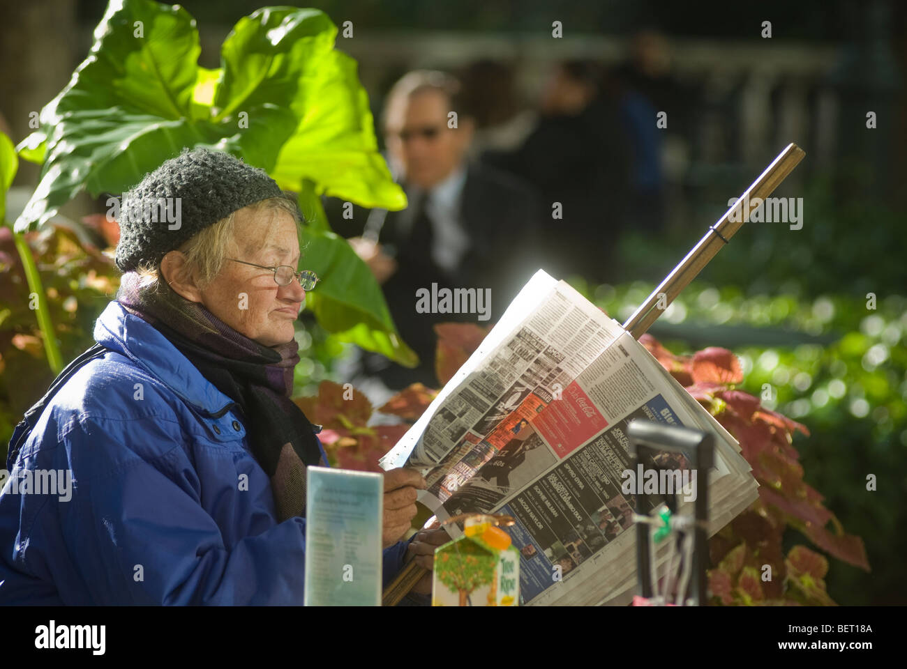 Un visitante de Bryant Park de Nueva York lee un periódico en el Bryant Park Sala de Lectura del parque Foto de stock