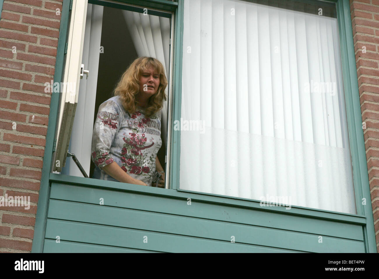 Mujer furiosa gritando desde la ventana de la habitación al visitante Foto de stock