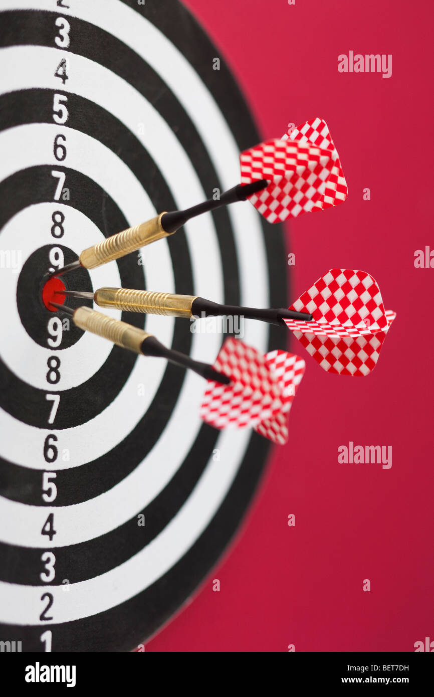 Rojo y blanco y negro tablero de dardos con tres dardos en bullseye Foto de stock