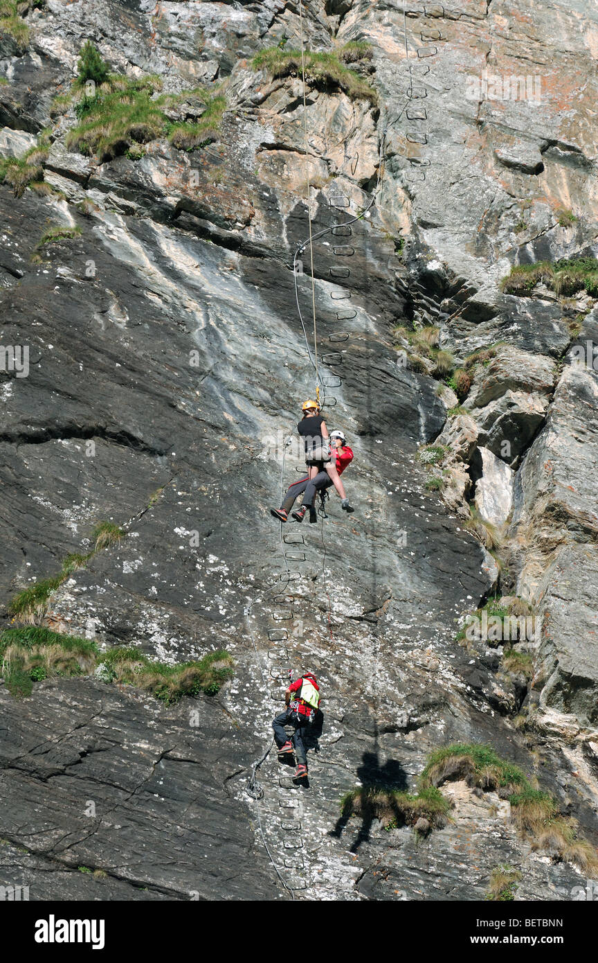 Helicóptero de rescate suizo winching socorrista y escalador / víctima de via ferrata / roca en los Alpes, Suiza Foto de stock