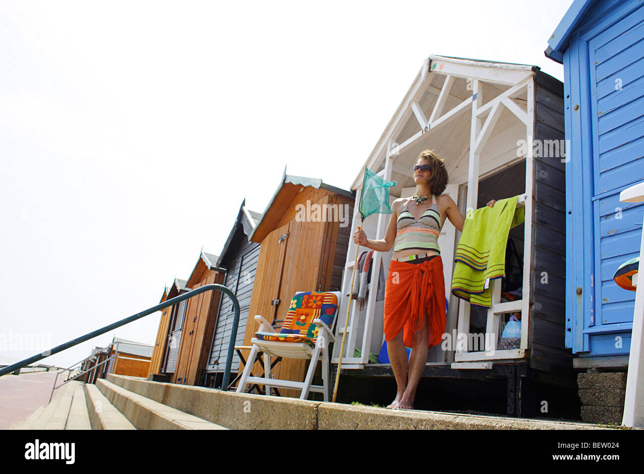 Mujer de pie fuera de una playa inglesa hut en un día de verano en inglés Foto de stock