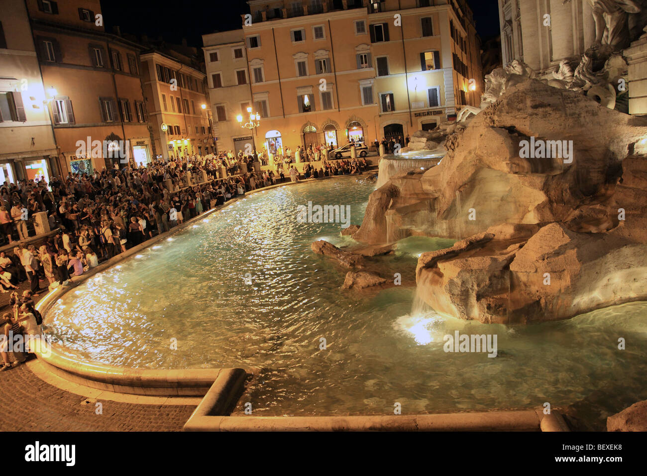 Las multitudes se reúnen alrededor de la fuente de Trevi (Fontana di Trevi) por la noche en Roma Foto de stock