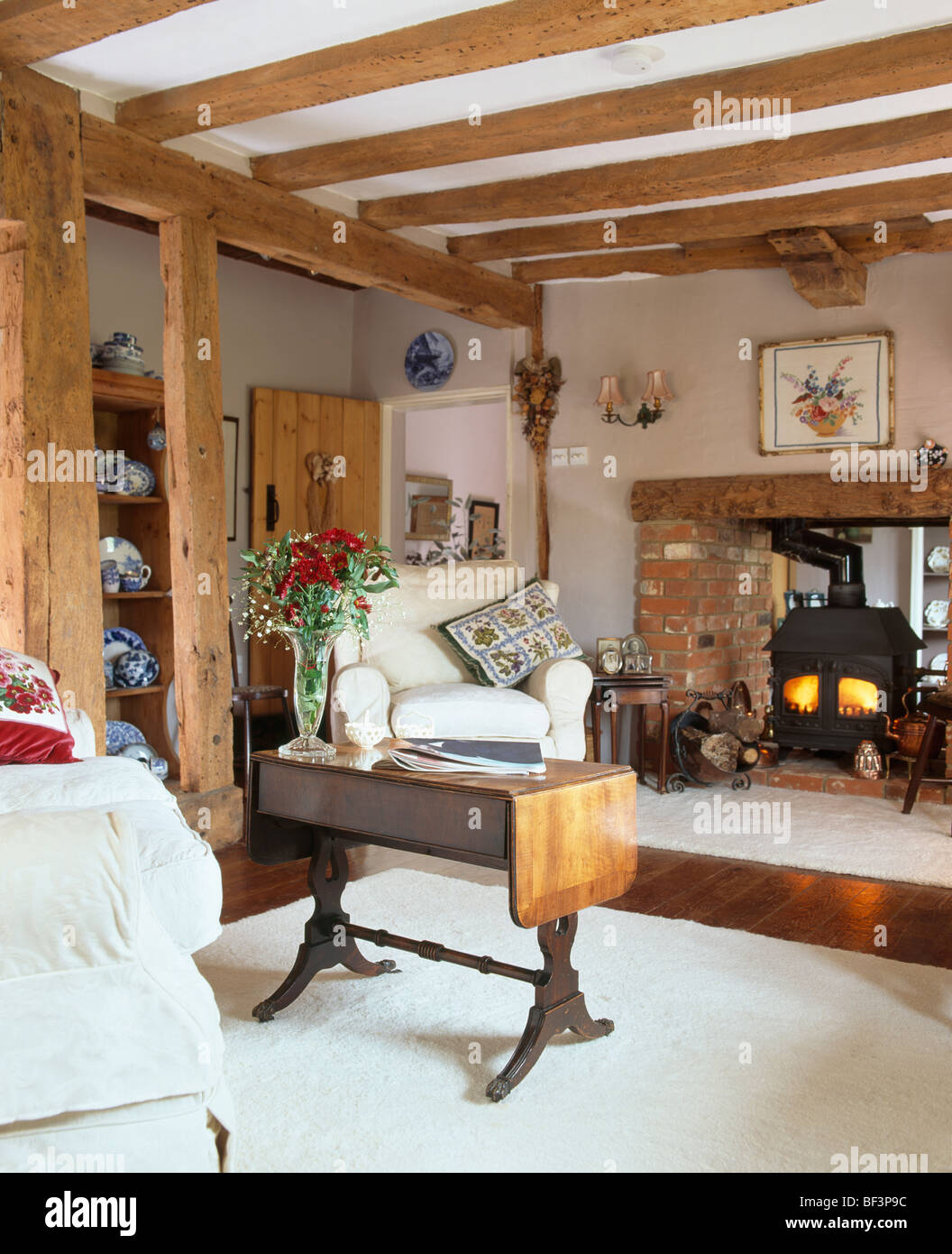 Mesa plegable en antiguas vigas en casa salón con estufa de leña y alfombra  blanca Fotografía de stock - Alamy