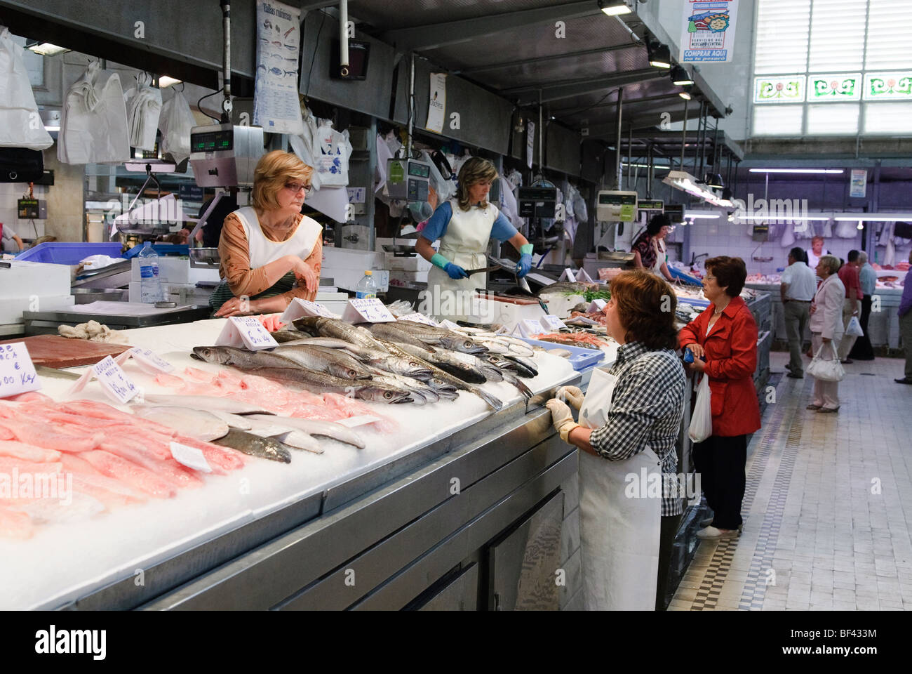 Las mujeres charlando en el puesto de venta de pescado en el mercado central, el mercado central de Valencia, España Foto de stock