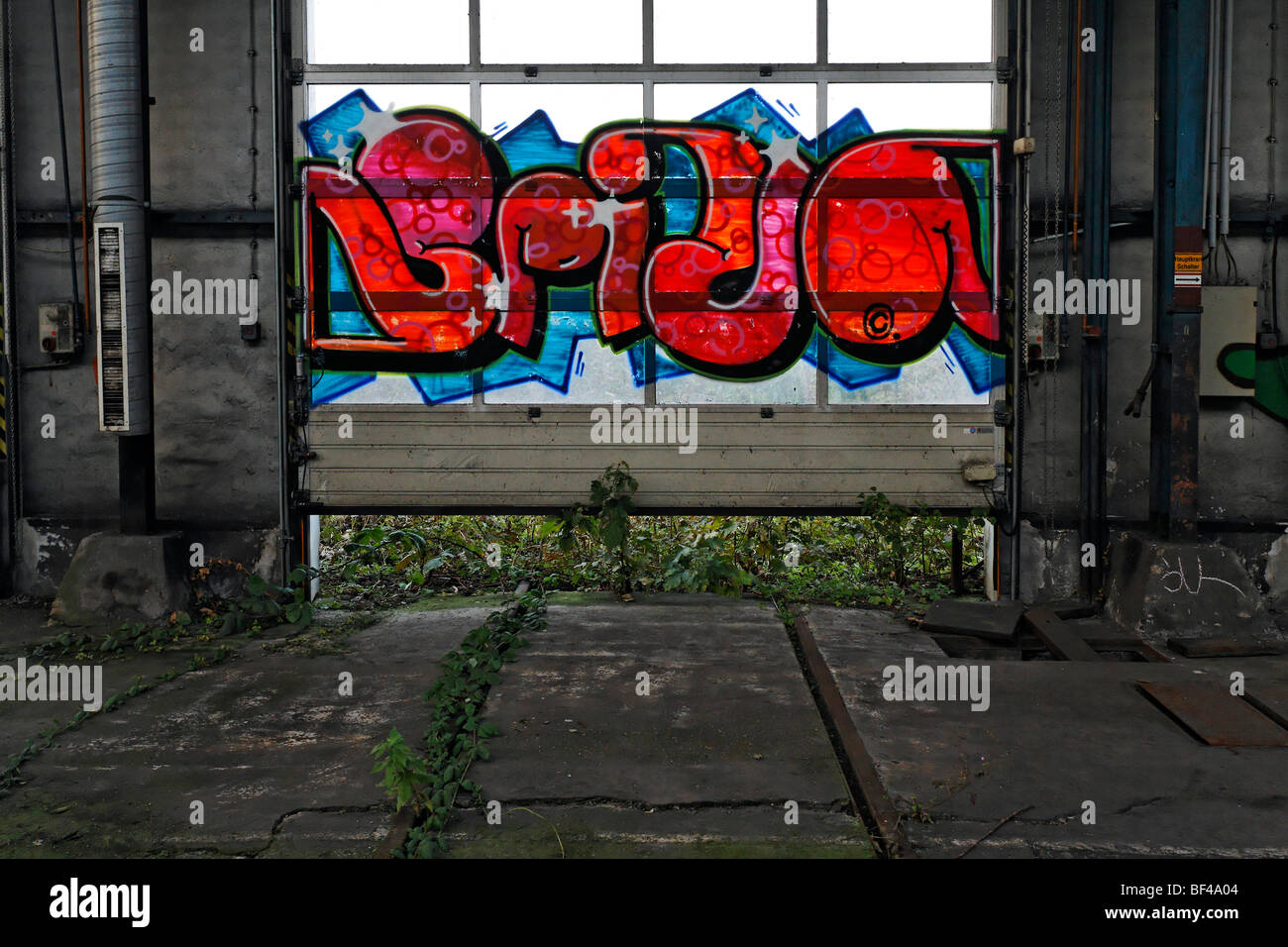 Nave industrial abandonada, puerta corrediza con graffiti, ex Ausbesserungswerk tienda de reparación de ferrocarriles alemanes, cerrada en 2003, Foto de stock
