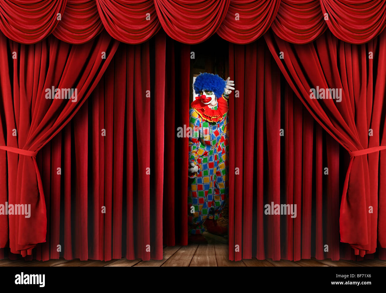 Espeluznante espeluznante payaso mirando a través de la etapa cortina blackout Foto de stock