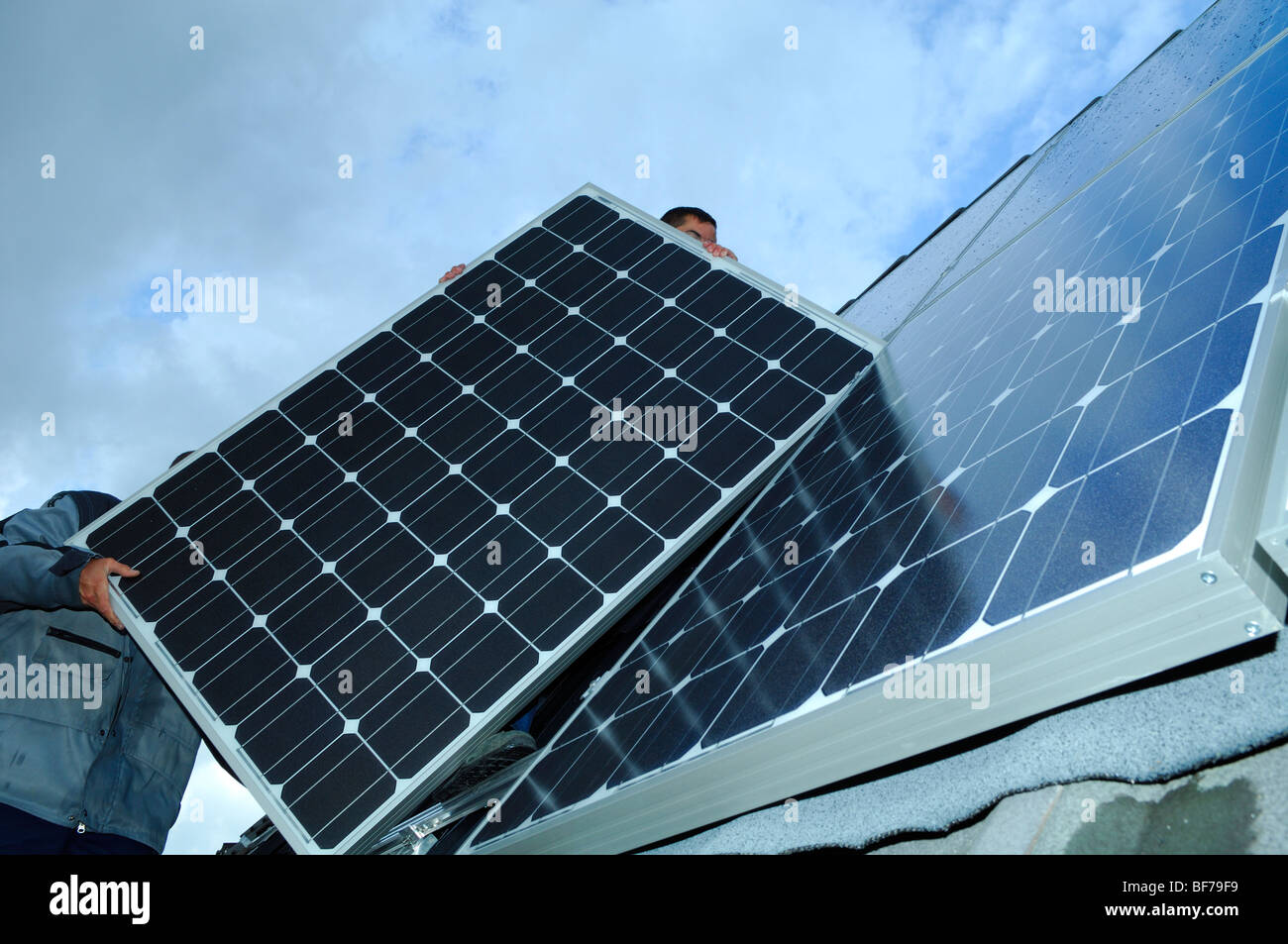 Los obreros la instalación de paneles solares fotovoltaicos en el techo de una casa privada Foto de stock