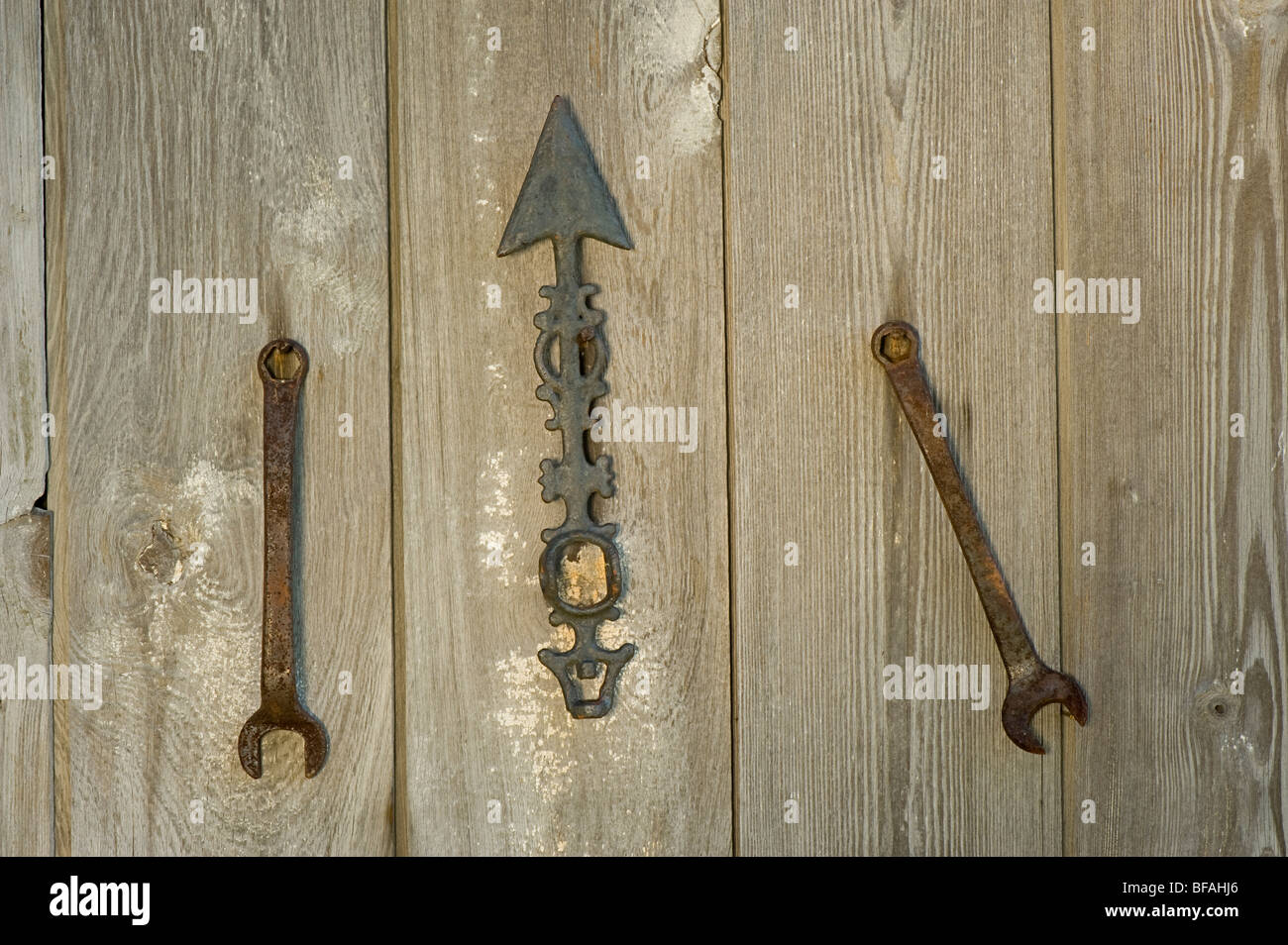 Dos llaves y una flecha colgando de un viejo cobertizo. Cada llave elige una dirección diferente que la indicada. Foto de stock