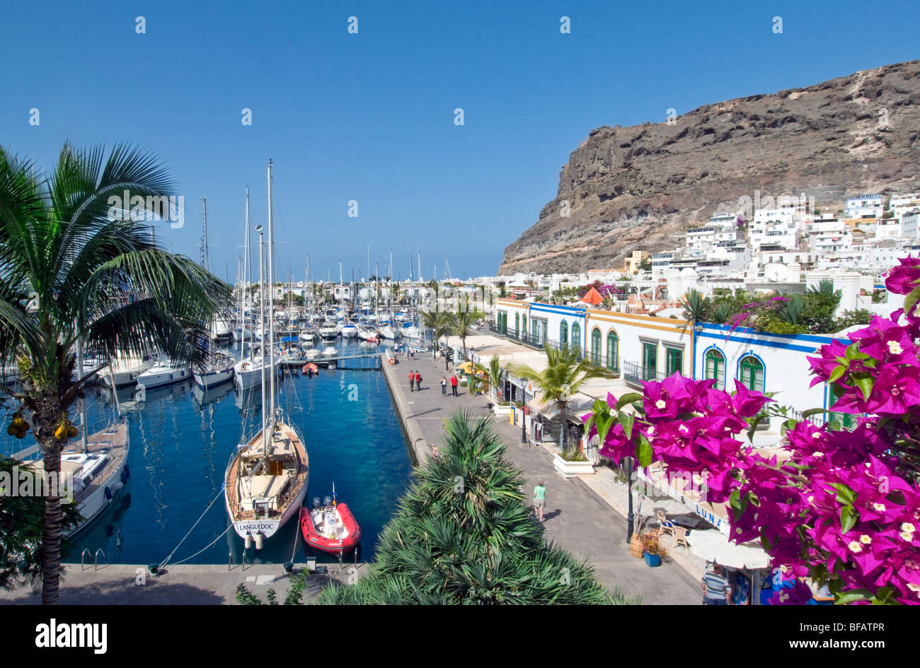 Puerto de Mogan vistas buganvillas flores a marina yacht paseo marítimo y los restaurantes, Gran Canaria, Islas Canarias Foto de stock