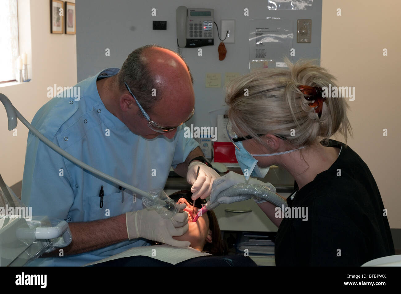 Dentista y asistente dental trabajando en un paciente joven en una cirugía dental moderna Foto de stock