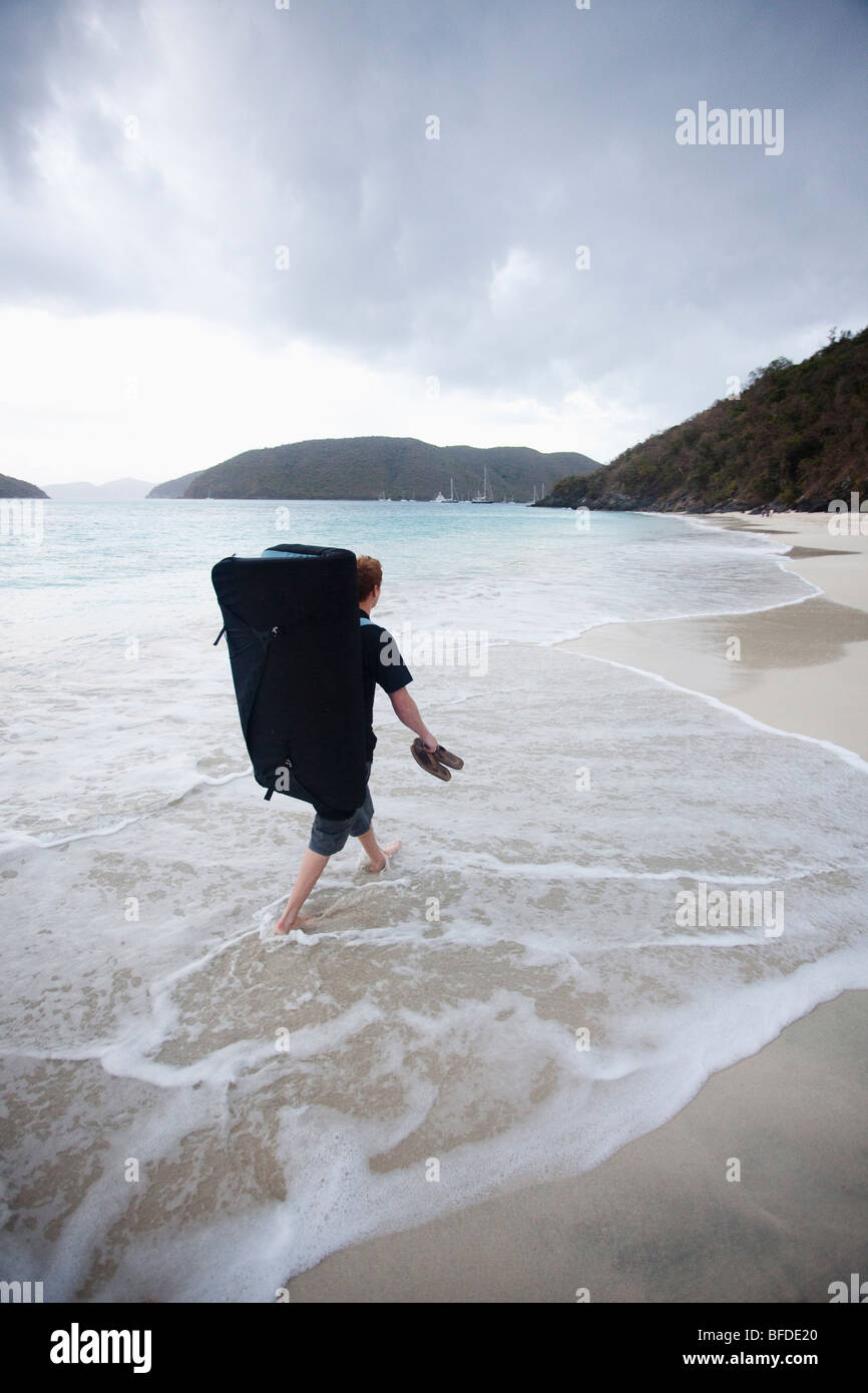 Un hombre camina en una playa de arena blanca mientras llevaba sus sandalias  y una almohadilla amortiguadora trepar rocas Fotografía de stock - Alamy