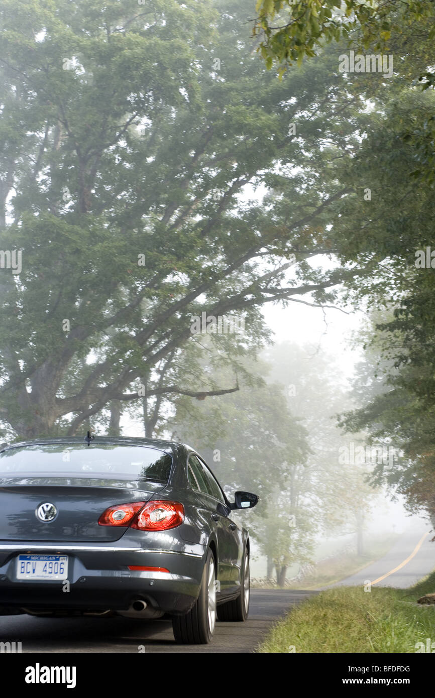 Un nuevo coche a lo largo de una carretera montañosa neblinoso. Foto de stock