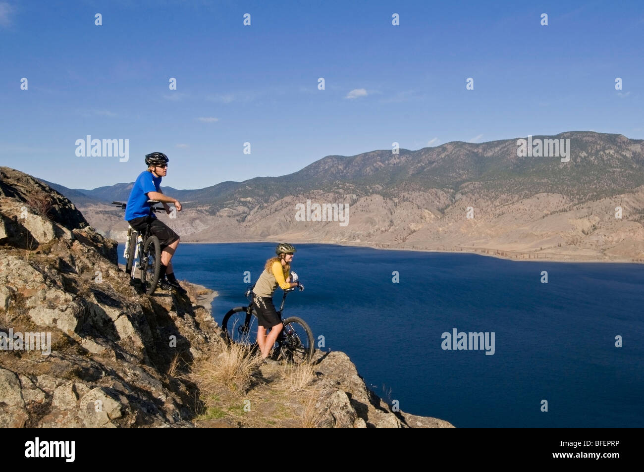 Pareja joven disfrutando de la vista de Kamloops Lake mientras el ciclismo de montaña en un hermoso día justo al oeste de Kamloops British Columbia Cana Foto de stock