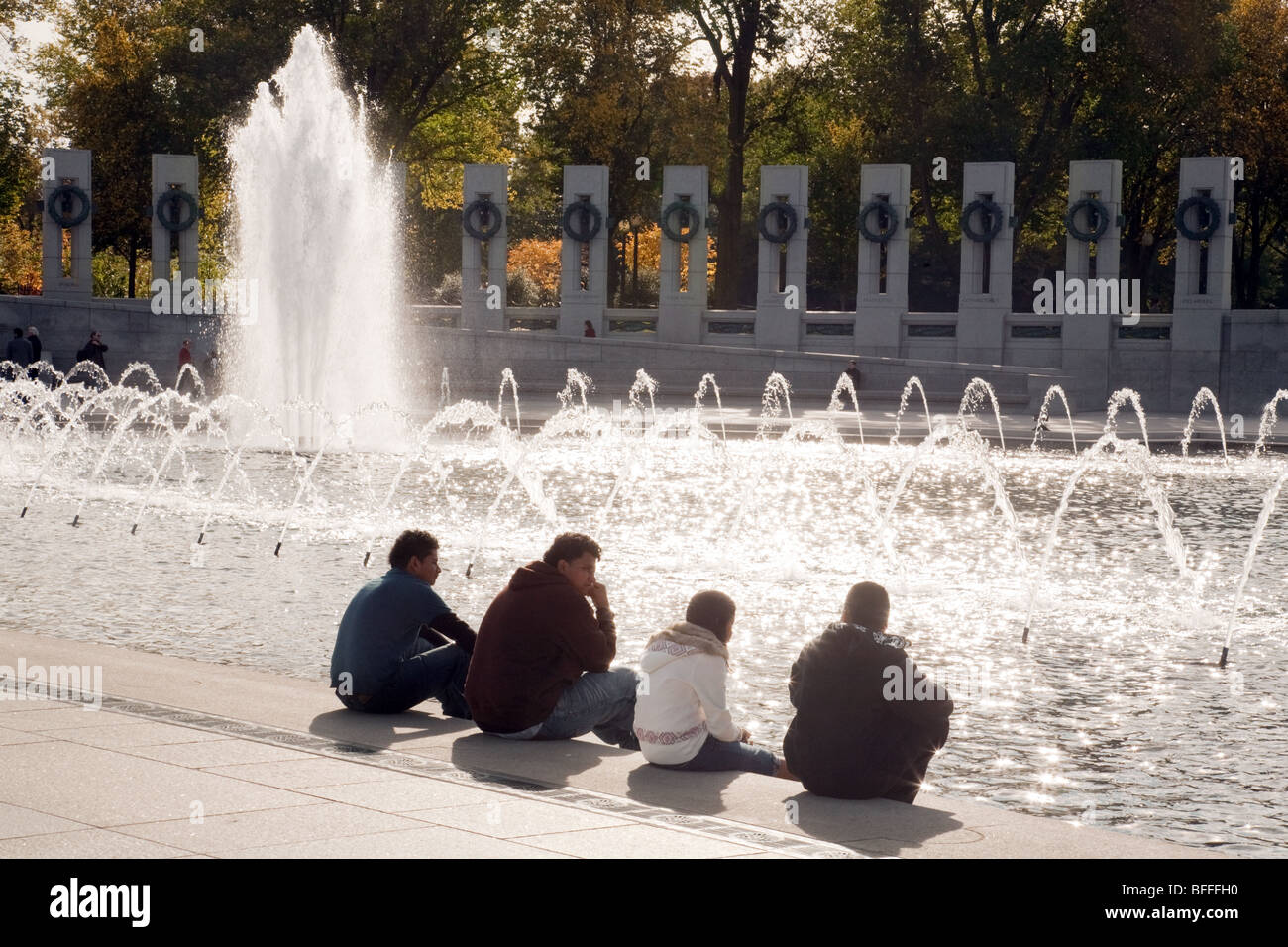 Cuatro adolescentes de sentarse junto a la fuente, el Memorial de la II Guerra Mundial, Washington DC, EE.UU. Foto de stock