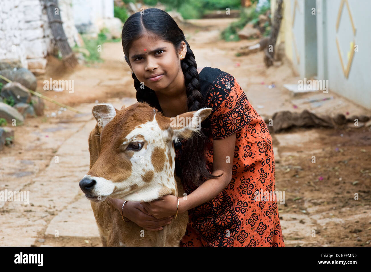 Indian Village joven chica abrazando un ternero en una aldea india. En Andhra Pradesh, India Foto de stock