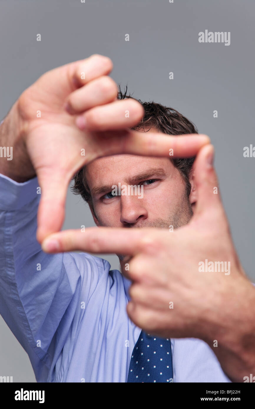 Empresario haciendo un bastidor con sus manos, se centran en su rostro manos borrosa. Foto de stock