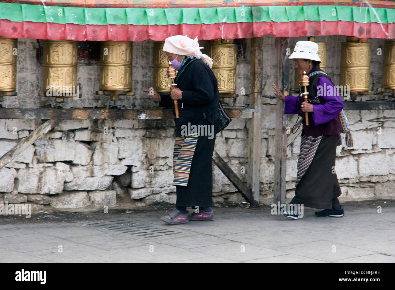Los peregrinos budistas tibetanos realizando la kora potala girando las ruedas de oración en Lhasa Foto de stock
