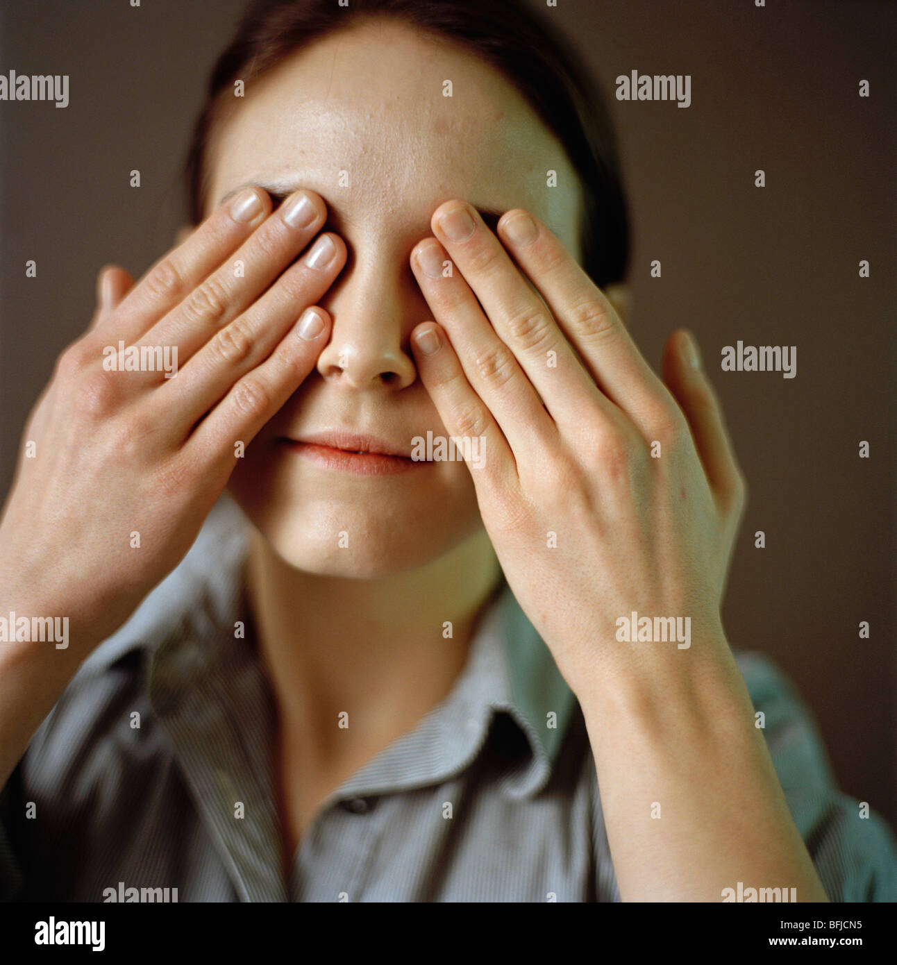 Retrato de una mujer con sus manos en sus ojos. Foto de stock