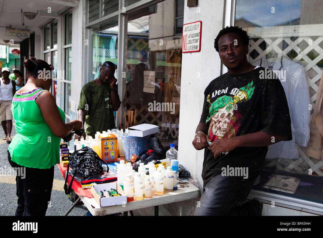 Hombre Negro de Antigua venta de artículos para el hogar desde un stand en una esquina de la calle de St Johns Town. Foto de stock