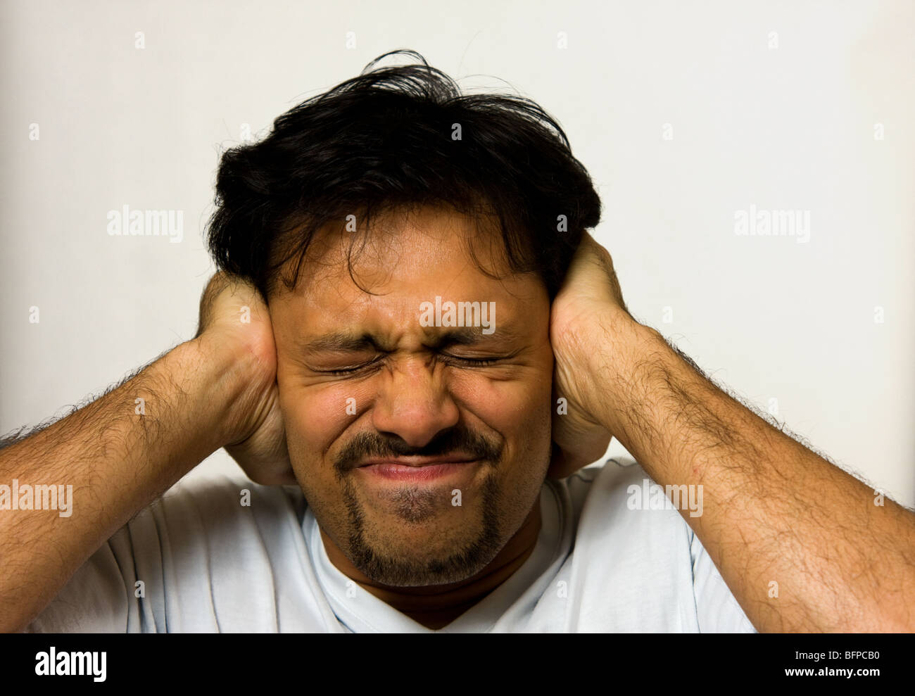 Hombre sujetando sus oídos para ahogar el ruido Foto de stock