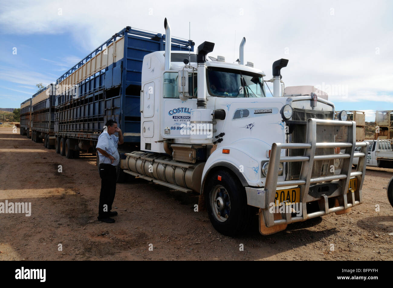 Un conductor de camión junto a su tren australiano de carretera ganadera en  un parque de camiones en Alice Springs, una de las pocas principales  paradas de boxes para sus instalaciones de