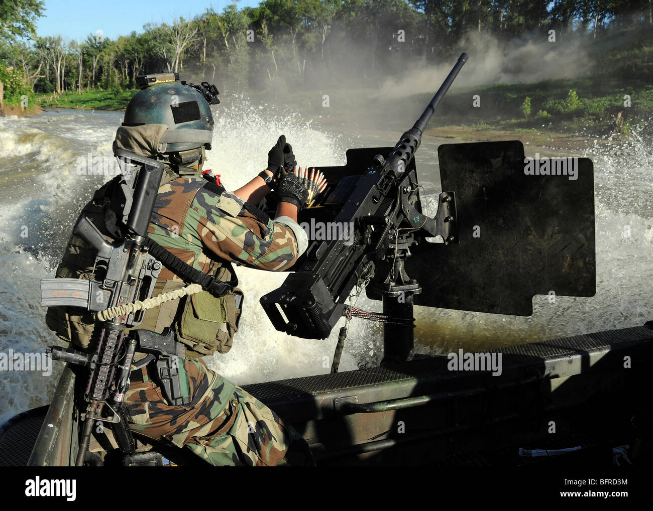 Un combatiente de guerra especial artesanía tripulante de recargar un M2 pesada ametralladora calibre .50 de barril. Foto de stock