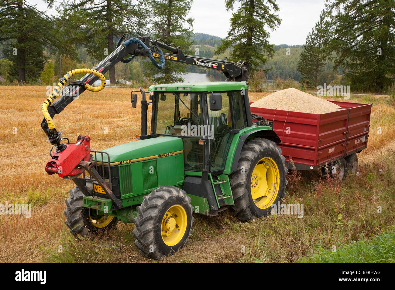 Tractor John Deere verde con remolque rojo cargado con grano cosechado , Finlandia Foto de stock