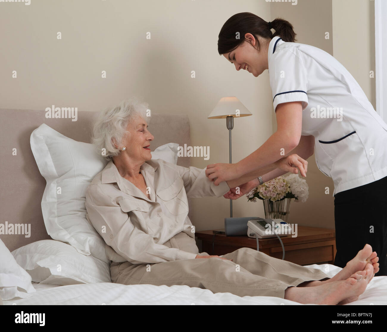 Enfermera de enrollar anciana la manga Foto de stock