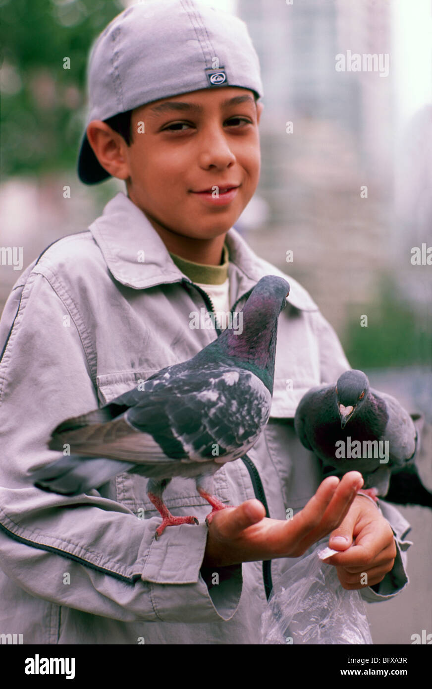 Joven la alimentación de las aves, los niños sosteniendo las palomas, la isla de Granville, Vancouver, BC, British Columbia, Canadá Foto de stock