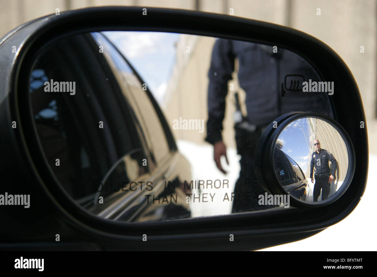 American cop se refleja en espejo de ala de coche. Foto de stock