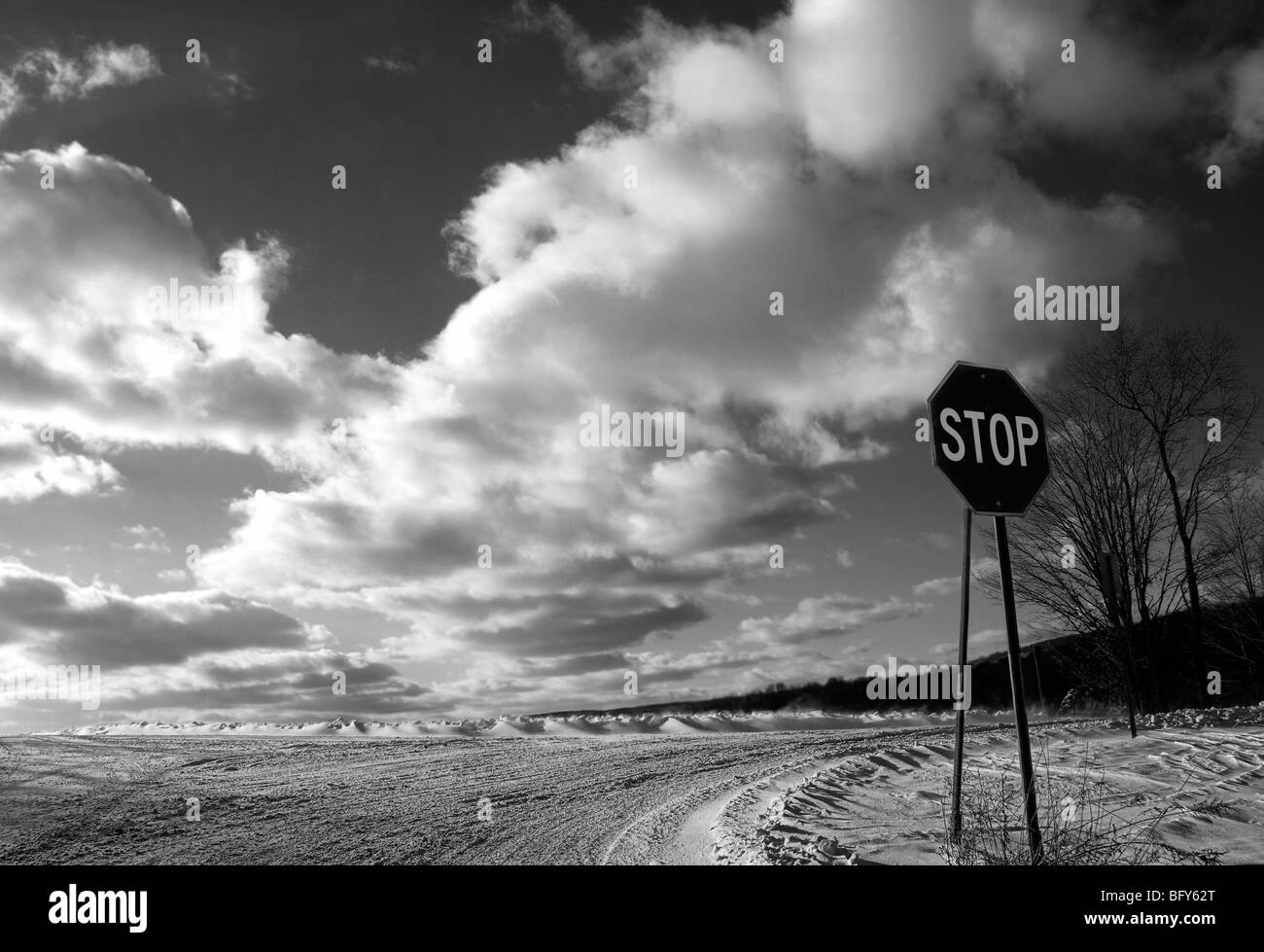 La señal de stop en carreteras cubiertas de nieve con brillantes nubes cielo espectacular Foto de stock