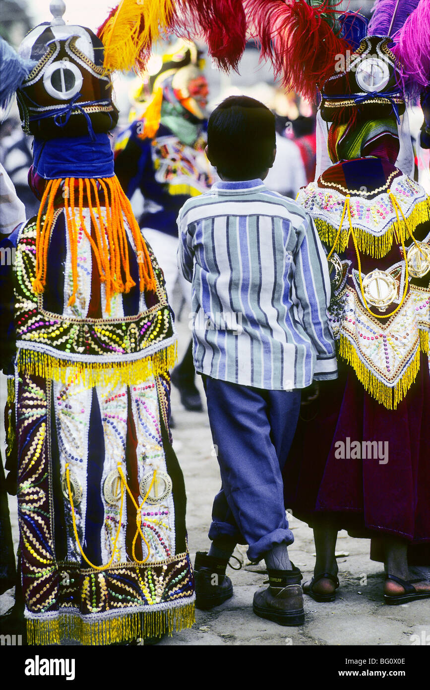 Dos chicos de disfraces que representan a los conquistadores españoles de  los mayas y que están participando en el festival danzas están uno a cada  lado de un amigo que no está