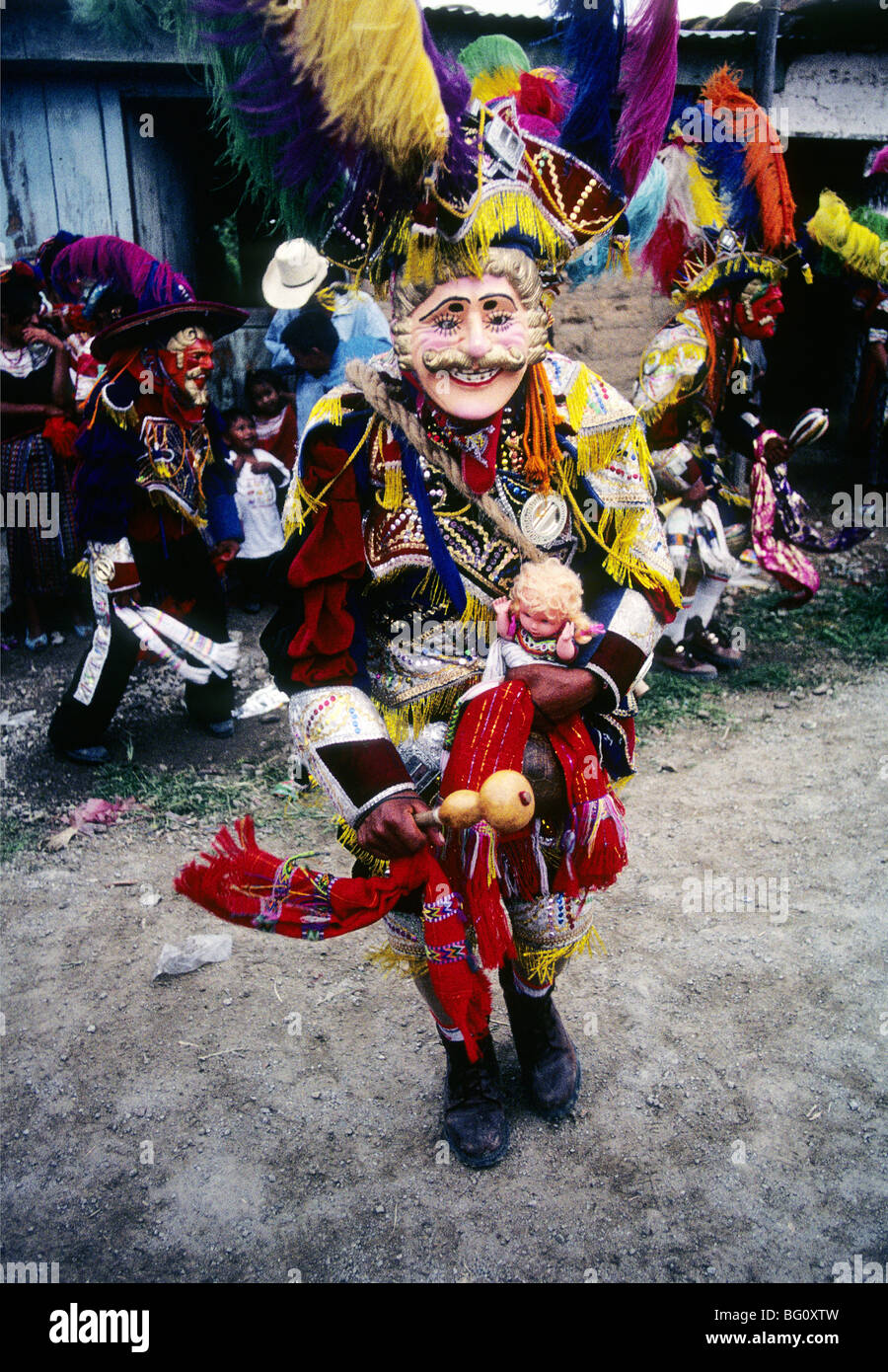 Un hombre vestido con el traje y con la máscara de un conquistador español  y la celebración de un baby doll blanco indicando que ha sido victorioso  sobre los mayas en ambas