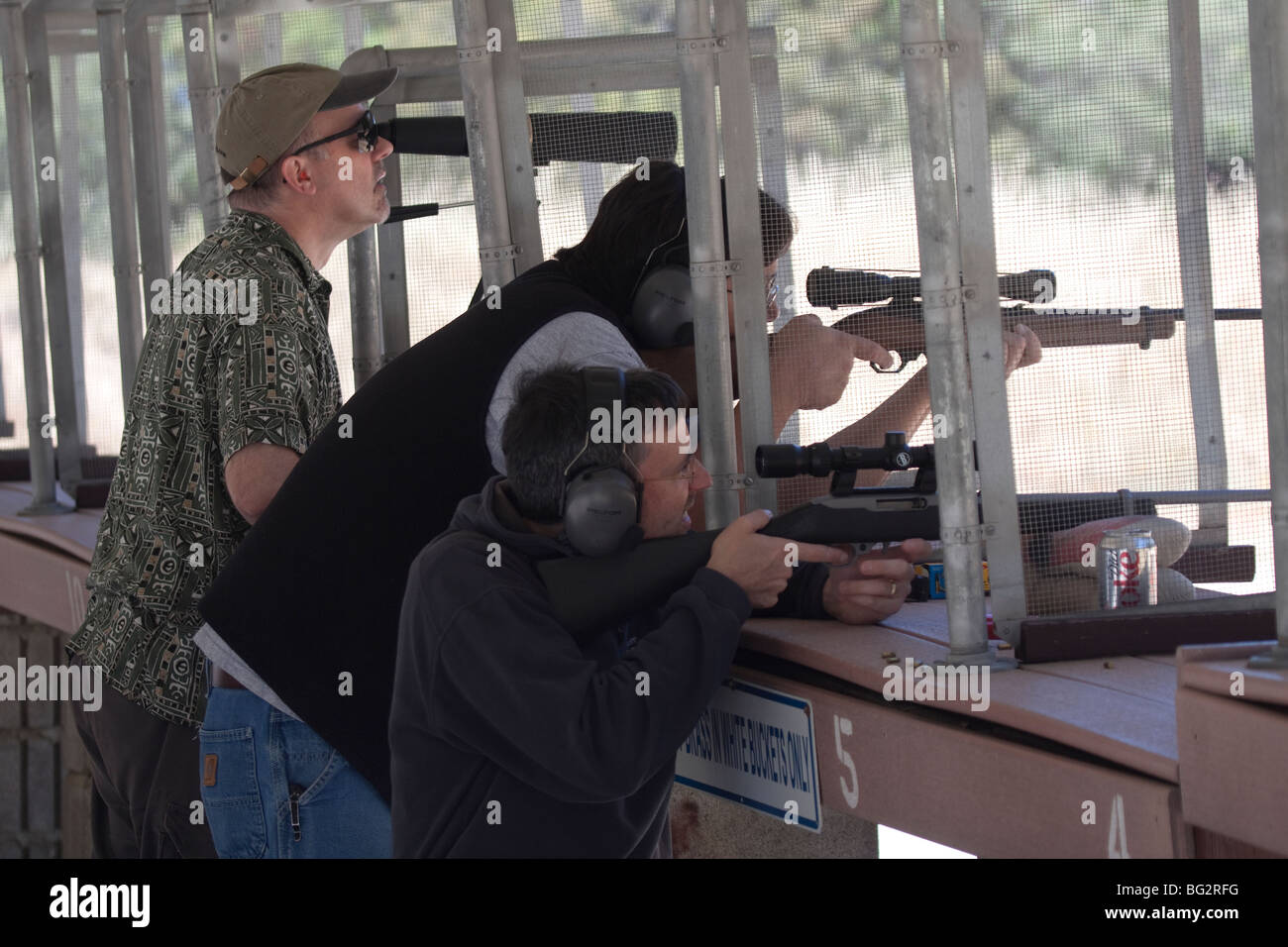 Tres hombres disparando rifles Ruger 10/22 utilizando endoscopios en la varilla y Los Altos Club PISTOLA pistola exterior gama Foto de stock