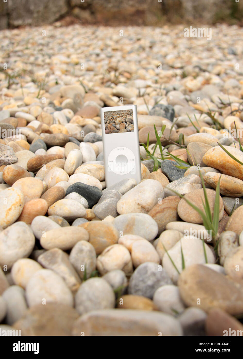 (Ipod Mp3 Player graved stile) en el suelo con rocas alrededor de él Foto de stock